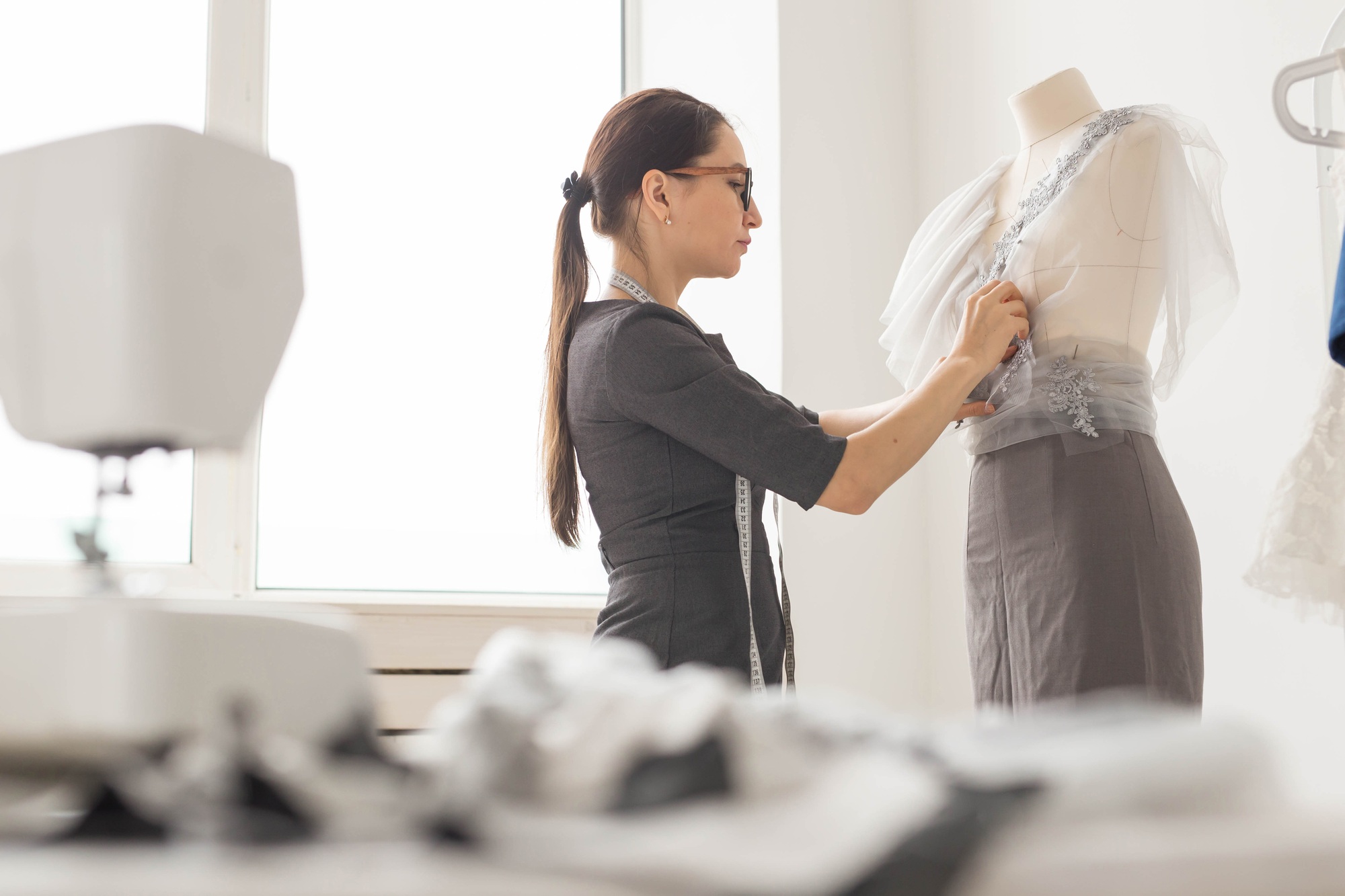 Dressmaker, tailor, fashion and showroom concept - Side view of female fashion designer measuring
